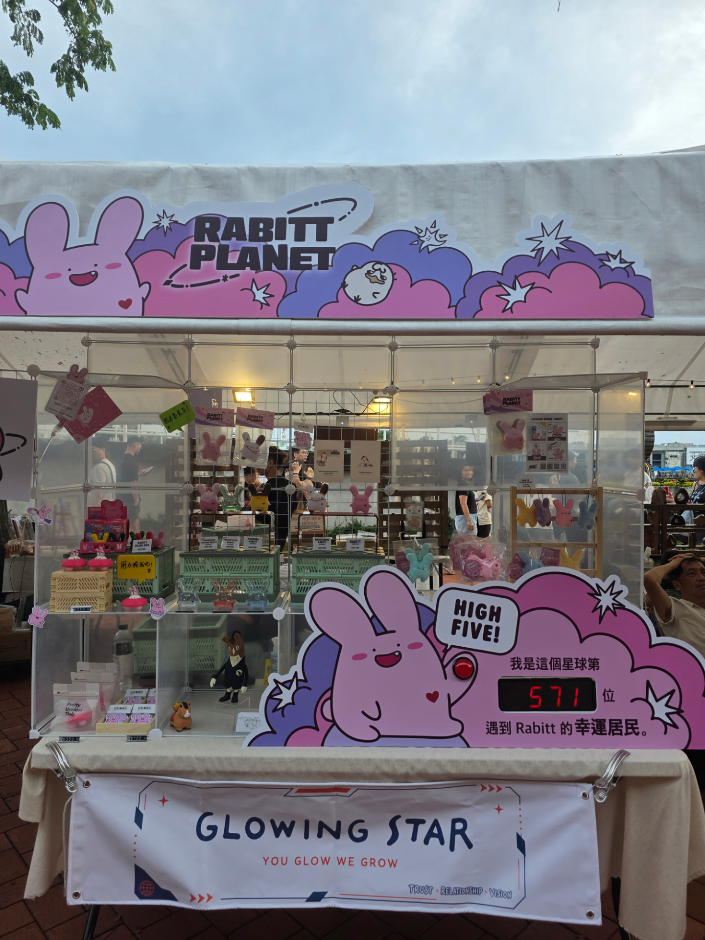 The Rabitt Planet stall at Shenxing Festival in Kaohsiung, with shelves of plush toys and blind boxes, the high-five counter and a Glowing Star banner on the front table