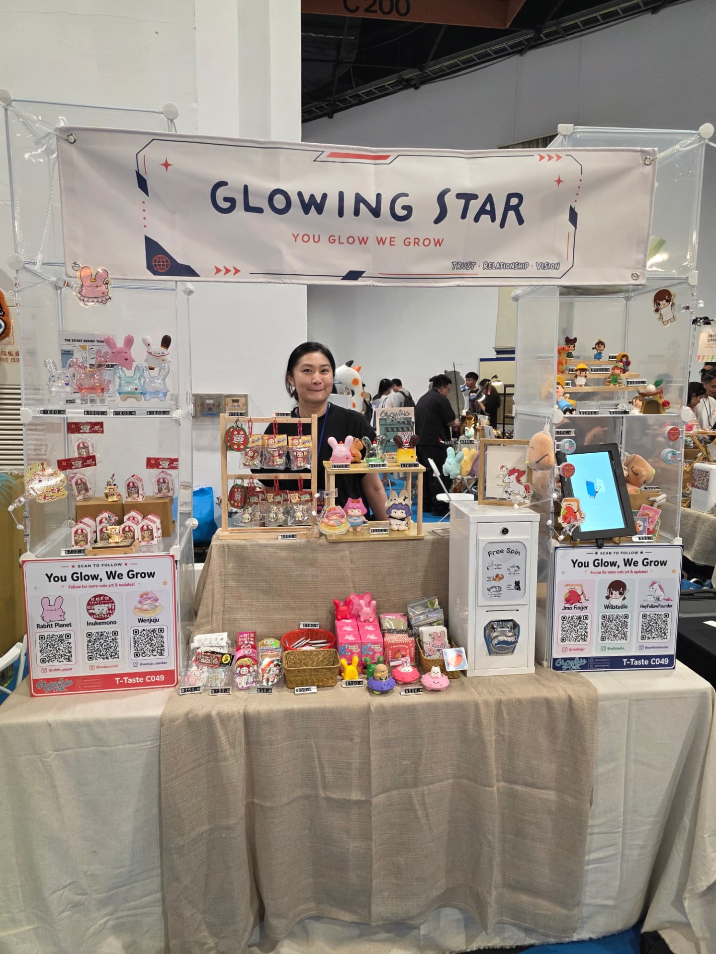 The Glowing Star booth at T-TASTE Taipei Creative Design Fair 2026, with the You Glow We Grow banner above a table of creator toys and editions
