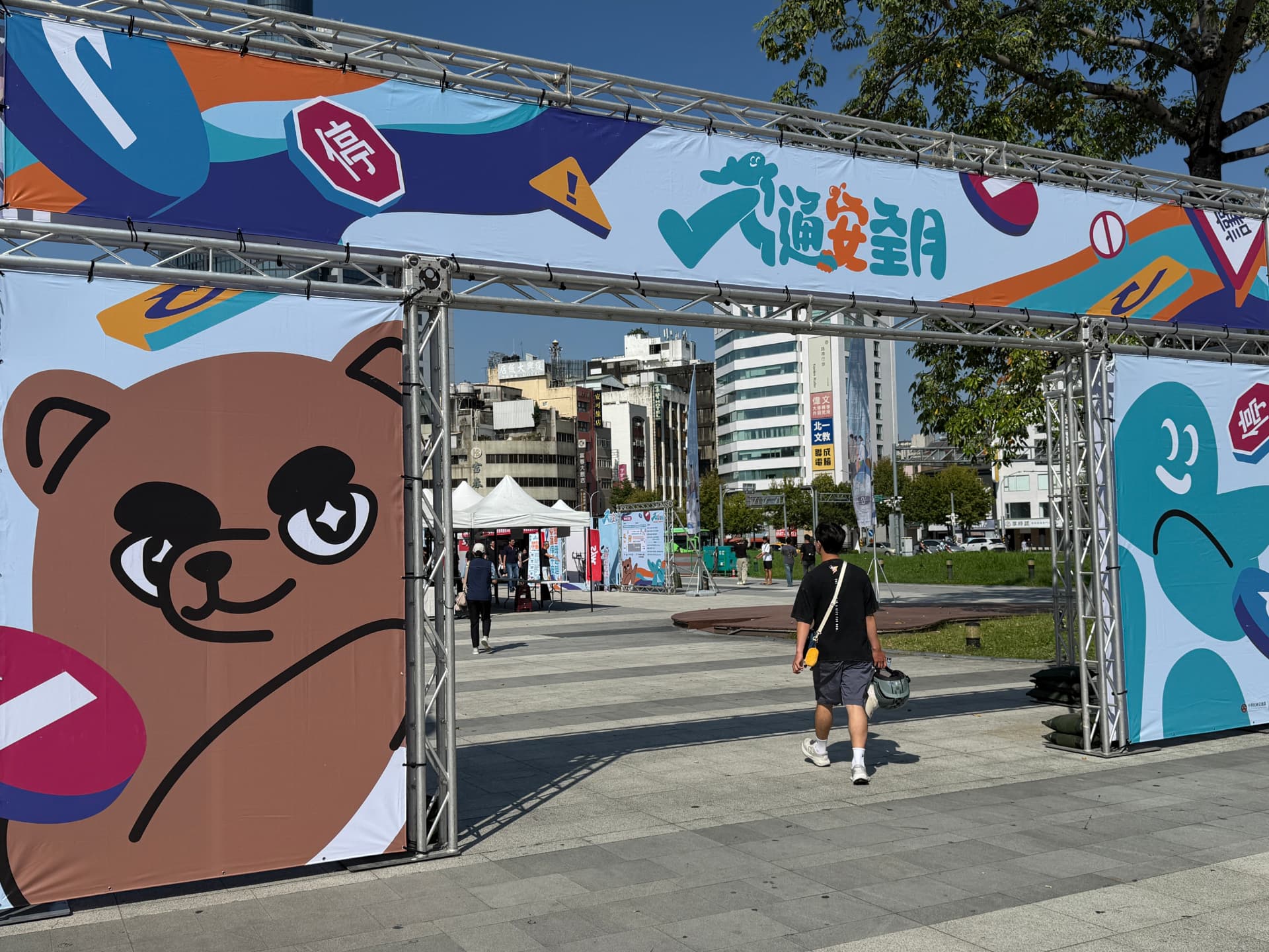 The 交通安全月 entrance archway at Taichung Station Front Plaza, with a visitor walking through toward the market tents